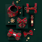 Collection of red plaid dog accessories including a bow, collar, and bandana on a dark green background.