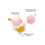 Cupcake-shaped toy with pink frosting, yellow cupcake body, and pink spiky ball on a white background.