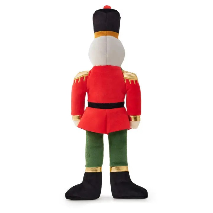 Plush dog toy resembling a nutcracker with red outfit and green pants on a white background