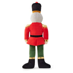 Plush dog toy resembling a nutcracker with red outfit and green pants on a white background