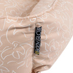 Close-up of a beige dog bed with white floral patterns and a 'Body Glove' label.