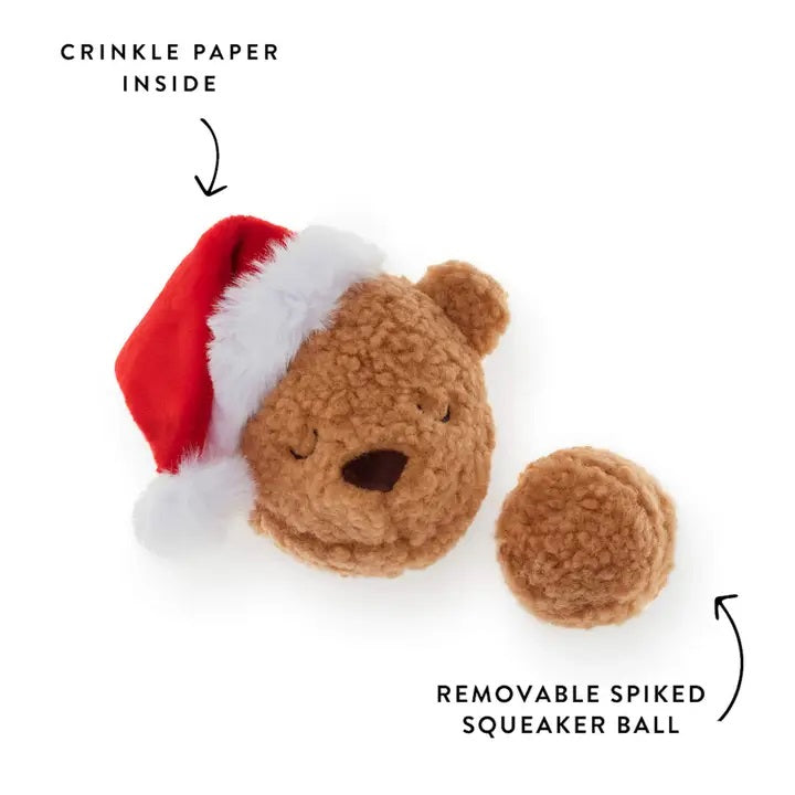 Brown bear-shaped dog toy with a red and white hat and removable spiked squeaker ball on a white background.